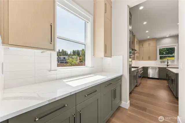 A bright and airy butler’s pantry offers additional prep and storage space with matching quartz countertops, modern cabinetry, and serene views through the window—seamlessly connected to the main kitchen for effortless flow.