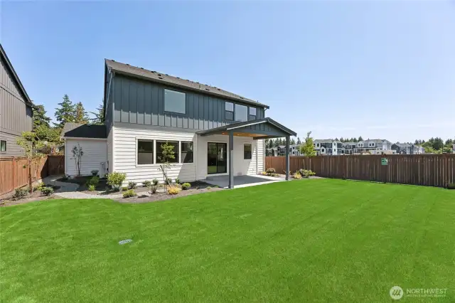 Expansive backyard with professional landscaping, privacy fencing, and a covered patio—perfect for entertaining, gardening, or enjoying the outdoors at home.