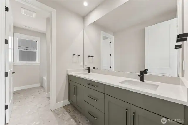 Stylish full bathroom featuring dual sinks, matte black hardware, quartz countertops, and a separate water closet with a tub/shower combo.