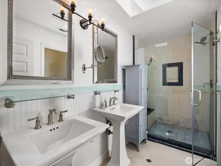 Primary bathroom with walk in shower stall & two sinks.