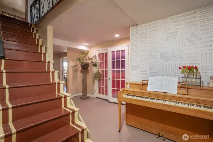 Heading downstairs, we have a large landing area, currently used as a music room, but you could pop a loveseat, desk, whatever, down here.  French doors lead to a flex room, adding to more possibilities.