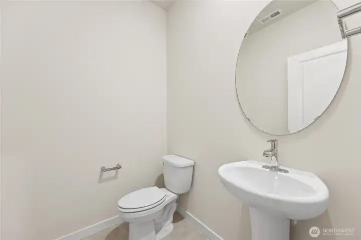 Powder room features elongated toilet and pedestal sink. Photo is representational. Actual home is under construction and materials, colors, and finishes will vary. See site agent for details.