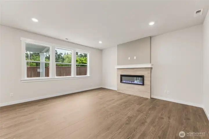 Family room with cozy fireplace and loads of windows. Actual home is under construction and materials, colors, and finishes will vary. See site agent for details.