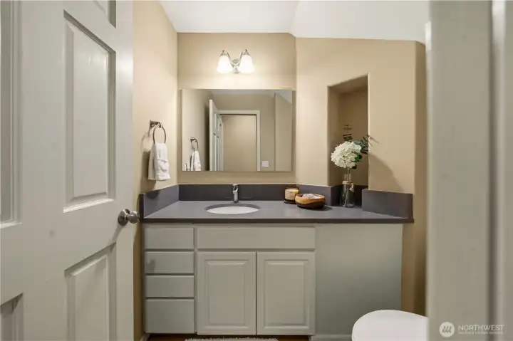 Main-level powder room with sleek quartz countertop ideally located near the garage for everyday convenience
