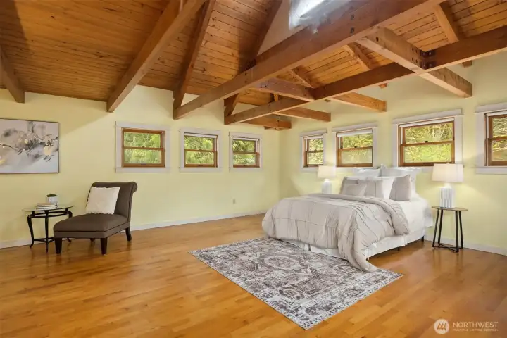 The spacious primary bedroom enjoys a vaulted ceiling with open beams and beautiful natural light.
