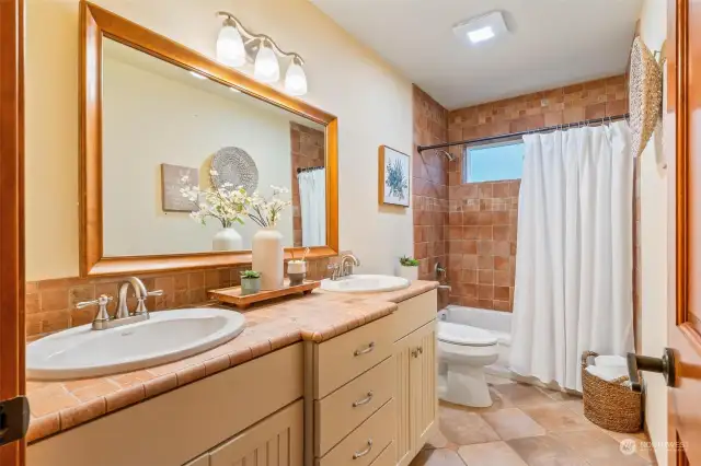 Shared full bathroom with modern fixtures, dual vanities, and a soaking tub for ultimate convenience.