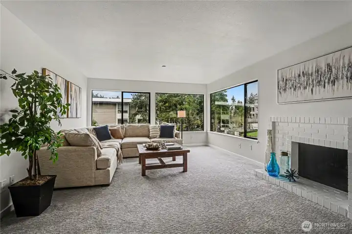 A spacious and inviting living room, complete with a fireplace for cozy evenings and expansive corner windows that fill the home with natural light.