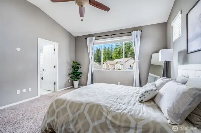 The spacious primary suite offers a tranquil retreat with tall vaulted ceilings, large windows for natural light, and direct access to a private full bathroom for ultimate convenience and comfort.