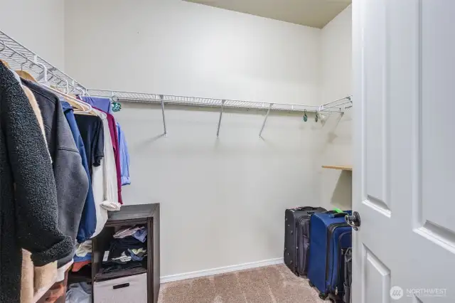 The spacious primary walk-in closet offers three sides of hanging storage and built-in shelving, providing ample space for organization and convenience.