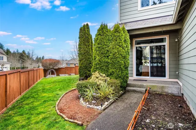 Fully fenced backyard with lush landscaping, raised garden beds, and a private patio off the dining area—perfect for outdoor entertaining or relaxing.