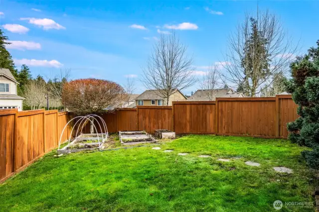 The fully fenced backyard features raised garden beds—perfect for growing your own vegetables, herbs, or flowers—along with lush landscaping and a private outdoor space to enjoy year-round.