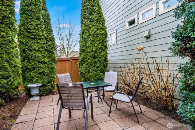 Enjoy a private outdoor retreat with a cozy seating area, surrounded by mature trees for added privacy. The paved patio is perfect for morning coffee, evening gatherings, or simply unwinding in your own serene space.