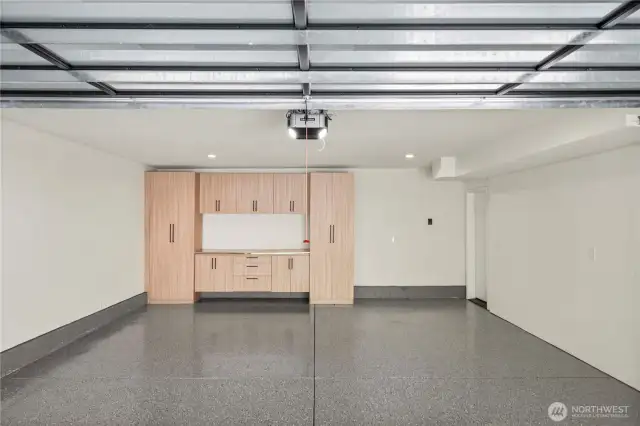 The finished garage features durable epoxy flooring and custom built-in cabinets, offering a clean, organized space with ample storage.