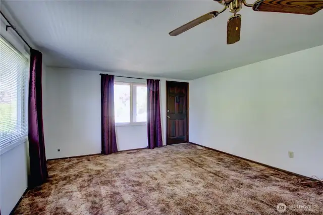 Welcoming living space with ceiling fan and free-standing gas stove