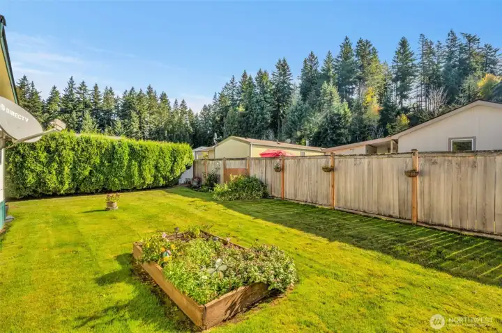 Private fenced backyard with raised flower bed.