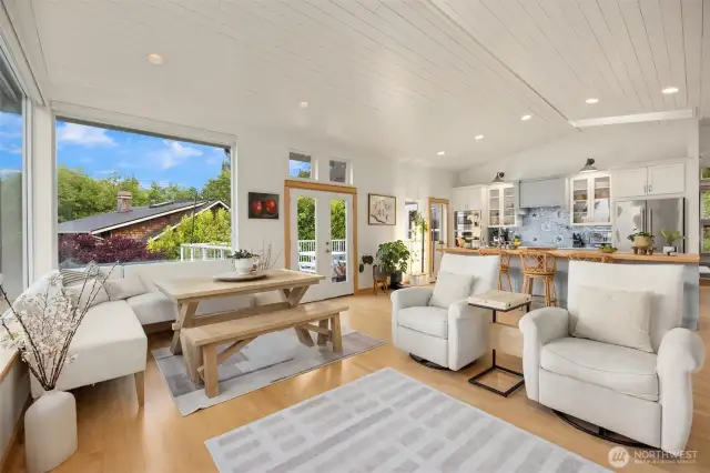 Looking back from the living room/dining area to the kitchen and double glass doors leading out the entertaining deck.
