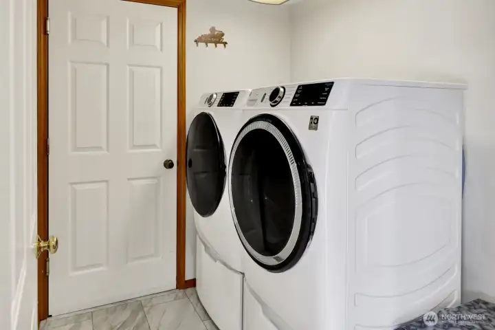 Laundry room located off of kitchen with door leading to garage.   Newer washer and dryer (2021) stays with the home.