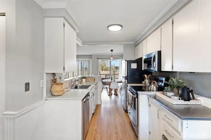 The bright and airy kitchen features crisp white cabinetry, stainless steel appliances, modern quartz countertops and easy care, vinyl plank flooring.
