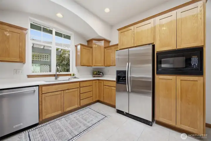 There is a built-in microwave adjacent to the side-by-side refrigerator.