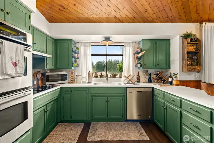 The stunning green cabinets go well with the wood ceiling.