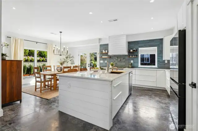 Kitchen and dining space. There are larger windows throughout the home and multiple doors leading to the outdoor spaces.