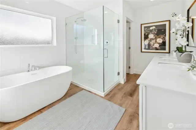 The connected spa-like primary bathroom with custom-tiled shower with a Grohe shower head, soaking tub with a Parallel Collection by Kohler tub-filler, Marble countertops, dual Kohler sinks and faucets, Kohler toilet.