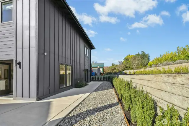 The backyard of the home with a landscaped terrace area that also has space and sun for a vegetable or flower garden.