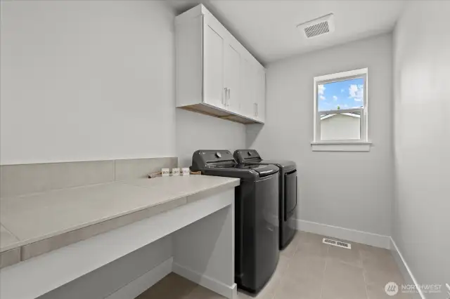 Upstairs laundry room with counterspace and storage.