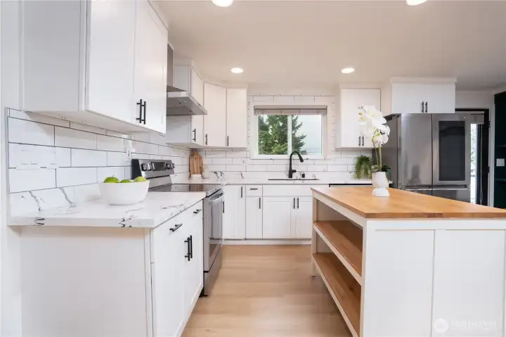 Modern, bright kitchen with white cabinets and stainless appliances.
