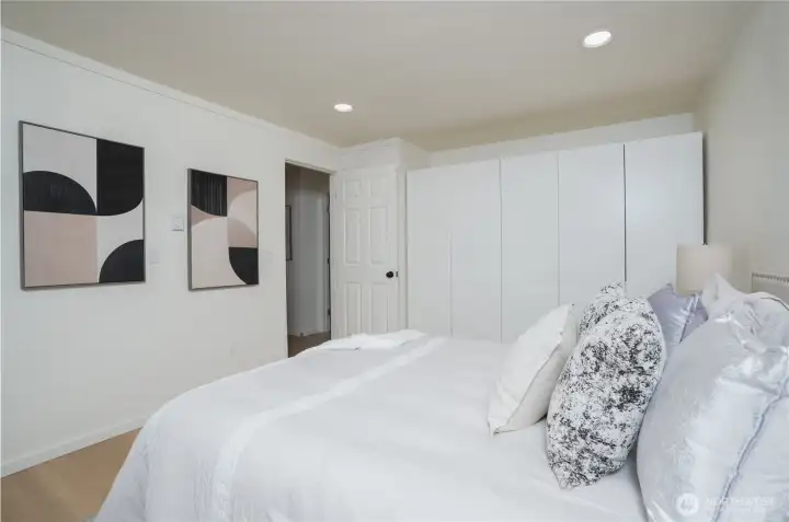 Minimalist bedroom with sleek, glossy custom closet for stylish storage.