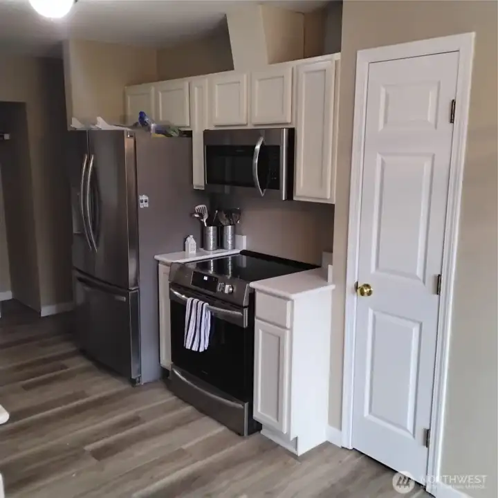 Other side of kitchen.  Stainless steel appliances stay.  New countertop and backslash. Door to pantry