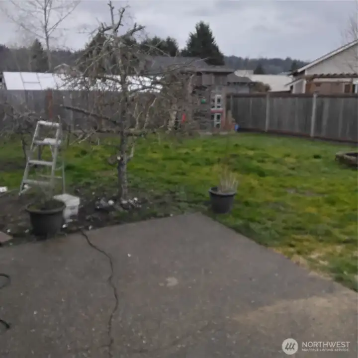 Fully fenced backyard with a fire pit.