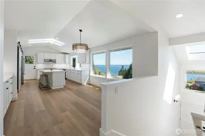 Light-filled main living area with large windows and warm wood flooring.