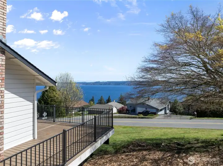 Relaxing deck space offering a picturesque peek-a-boo view of the water through mature trees.