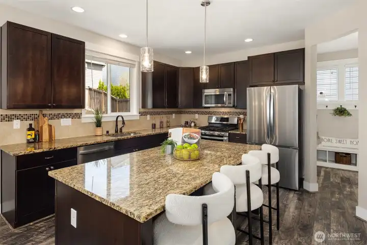 Functional kitchen with a large island offering additional seating space. Enjoy slab granite counters, stainless appliances and a tile backsplash