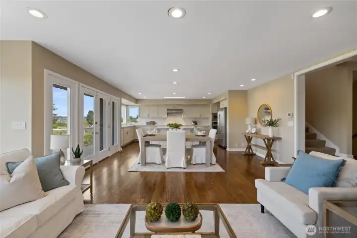 Light-filled living room with expansive windows capturing stunning water views, cozy fireplace, and seamless access to view deck.