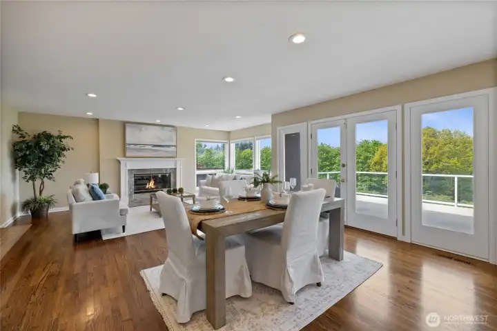Comfortable yet refined living space anchored by a fireplace and surrounded by windows showcasing lush greenery and water views.