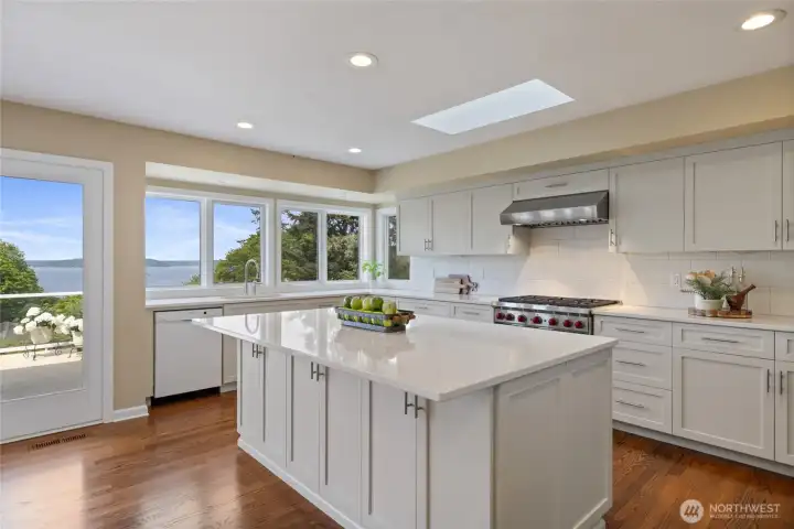 Spacious chef’s kitchen with oversized quartz island, abundant cabinetry, and open dining area positioned to enjoy natural light and scenery.