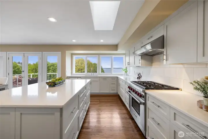 Beautifully updated kitchen featuring quartz counters, skylight for added natural light and panoramic outlooks. Chef-caliber kitchen with Viking gas range, custom cabinetry, and sleek finishes, all complemented by scenic water views.