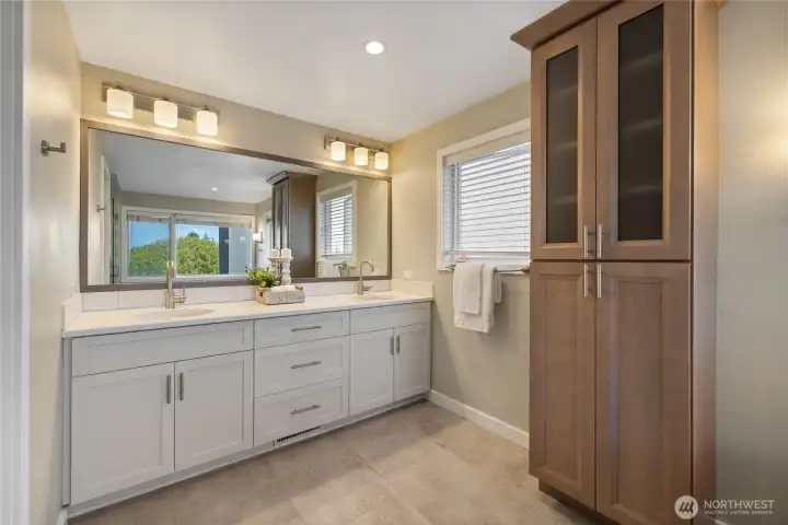 Elegant double vanity with quartz countertops, dual sinks, designer lighting, and abundant cabinetry for optimal storage and everyday functionality.