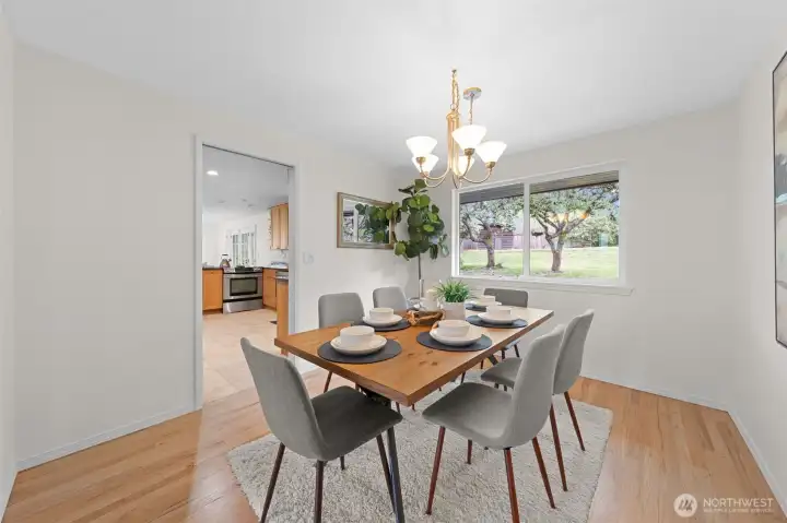 Bright dining area with a large window framing views of the backyard and mature landscaping. Positioned next to the kitchen for a seamless setup when hosting Bright dining area with a large window framing views of the backyard and mature landscaping. Positioned next to the kitchen for a seamless setup when hosting