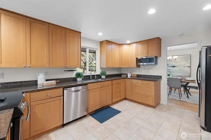 Expansive kitchen layout with abundant cabinetry, granite counters, and stainless steel appliances. Large window above the sink frames backyard views and brings natural light into the kitchen. Expansive kitchen layout with abundant cabinetry, granite counters, and stainless steel appliances. Large window above the sink frames backyard views and brings natural light into the kitchen.