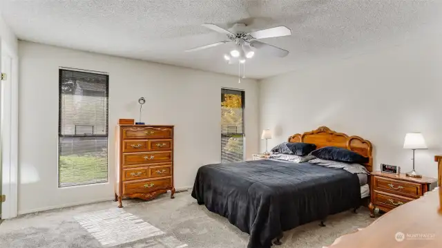 The cozy primary bedroom upstairs featuring plush carpets, floor to ceiling windows, and a primary en suite - creating a restful retreat.