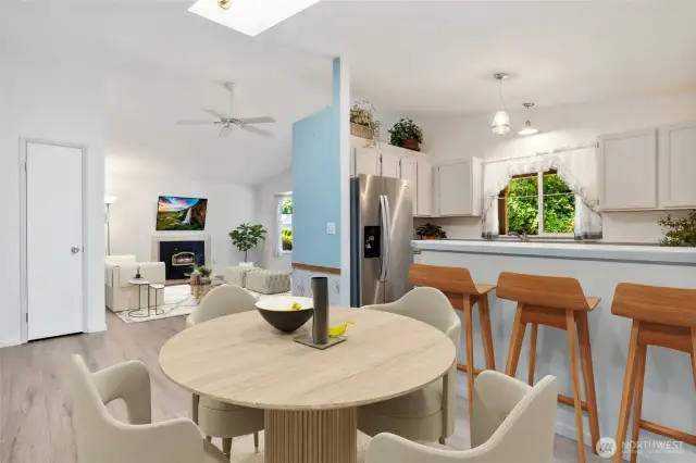Thoughtfully designed for connection—this open-concept kitchen and dining space features a breakfast bar, skylight, and seamless flow into the living area. (Virtually Staged)