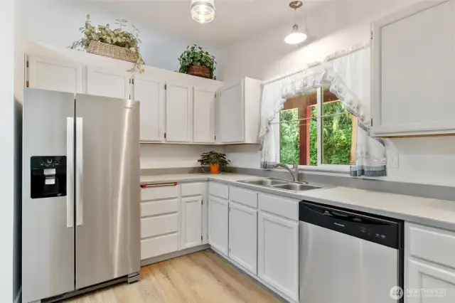 Clean and functional kitchen with stainless appliances, classic cabinetry, and a window above the sink that brings in soft natural light.