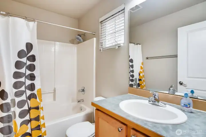 Bright 2nd bathroom featuring a single vanity and a relaxing soaking tub.