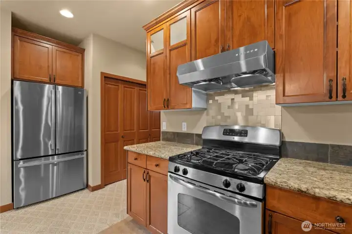 The kitchen includes an impressive gas range and oven, a powerful (but quiet) Fotile hood, dishwasher, microwave, accented by a deep double-basin sink and geometric backsplash behind the stove.
