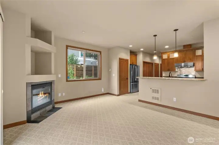 The great room is spacious, filled with natural light. The gas fireplace with blower can be seen on the left, with built-in display niches above.