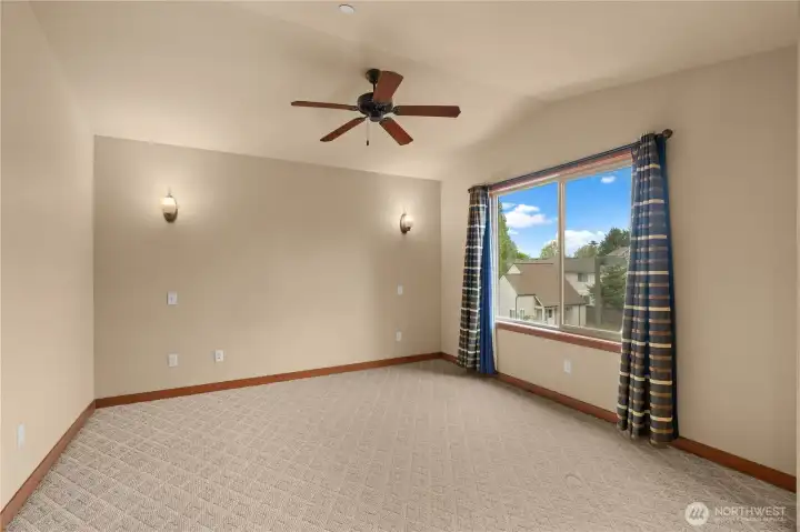 The primary bedroom is spacious and bright with a big window, vaulted ceilings and fan.