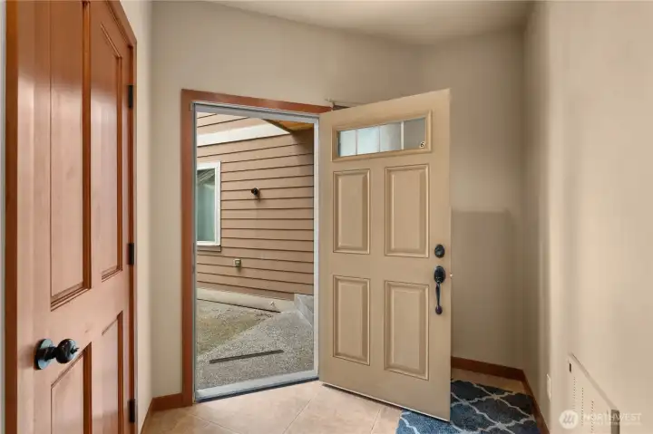 The front area has a deep entryway, with the stairs out of frame to the right. The door to the left accesses the garage.